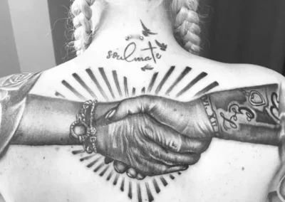 Schwarz-weißes Rücken Tattoo - Zwei Menschen geben sich die Hände vor einem stilisierten Herz