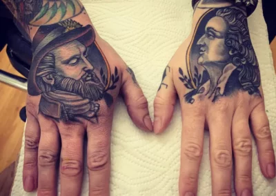 Farbige Hand Tattoos - jeden Handrücken ziert ein Abbild eines Herren, einmal aus der viktorianischen Zeit und aus dem Barock