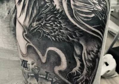 Schwarz-weißes Arm Tattoo - Fantasy-Greifvogel fliegt über einer zerspringenden Uhr